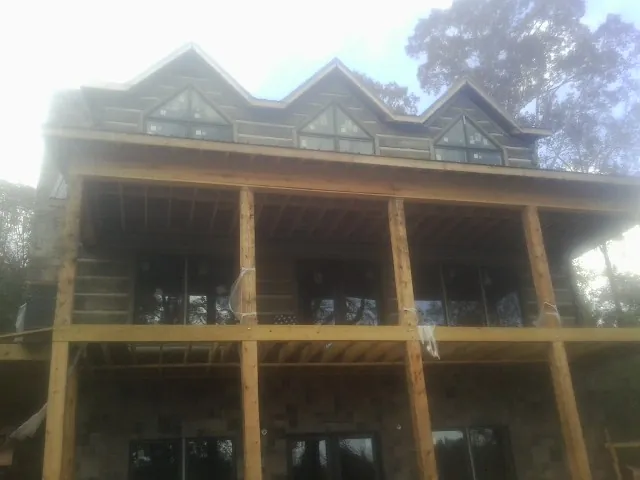 Dormers and porch framing on a large log home under construction — Roof Coating work by our crew in Sheffield