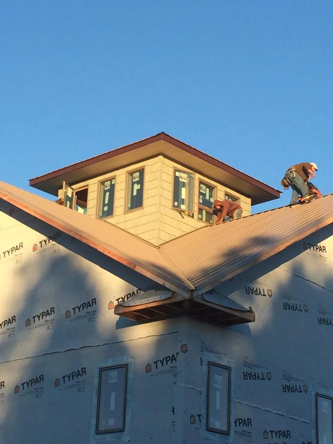 Roofers working around a rooftop cupola on a new metal roof at sunset — Roof Waterproofing in Sheffield by Roofing Brothers